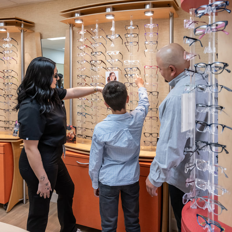 staff member help a little boy choosing a new pair of eyeglasses
